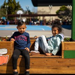 Two young students seated in the multi-purpose flowerbed and bench garden project